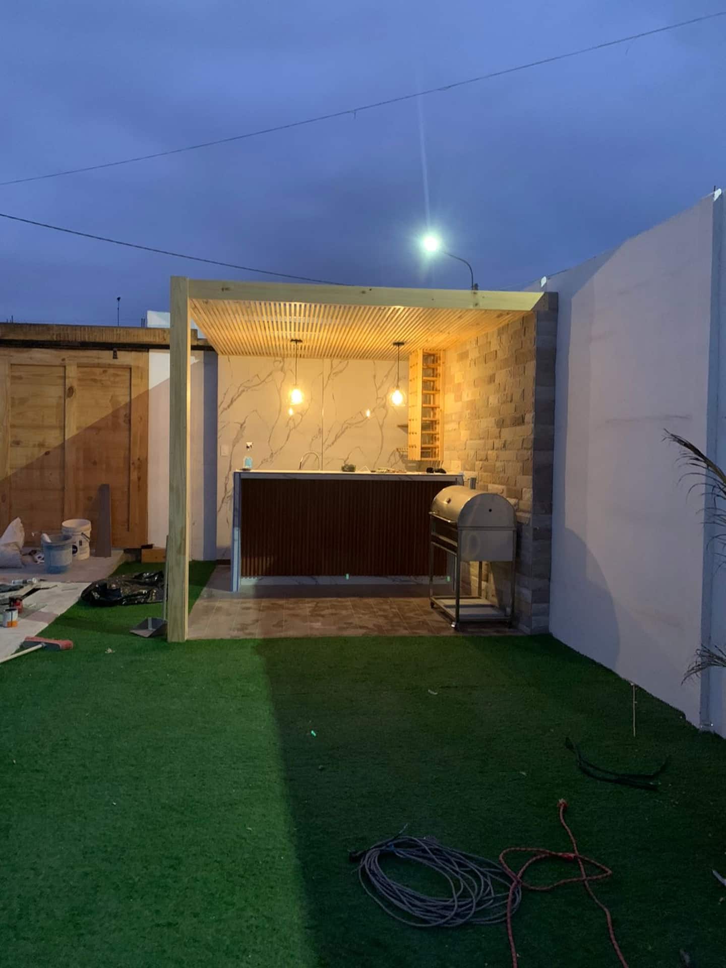 Bar exterior con pérgola de madera y parrilla