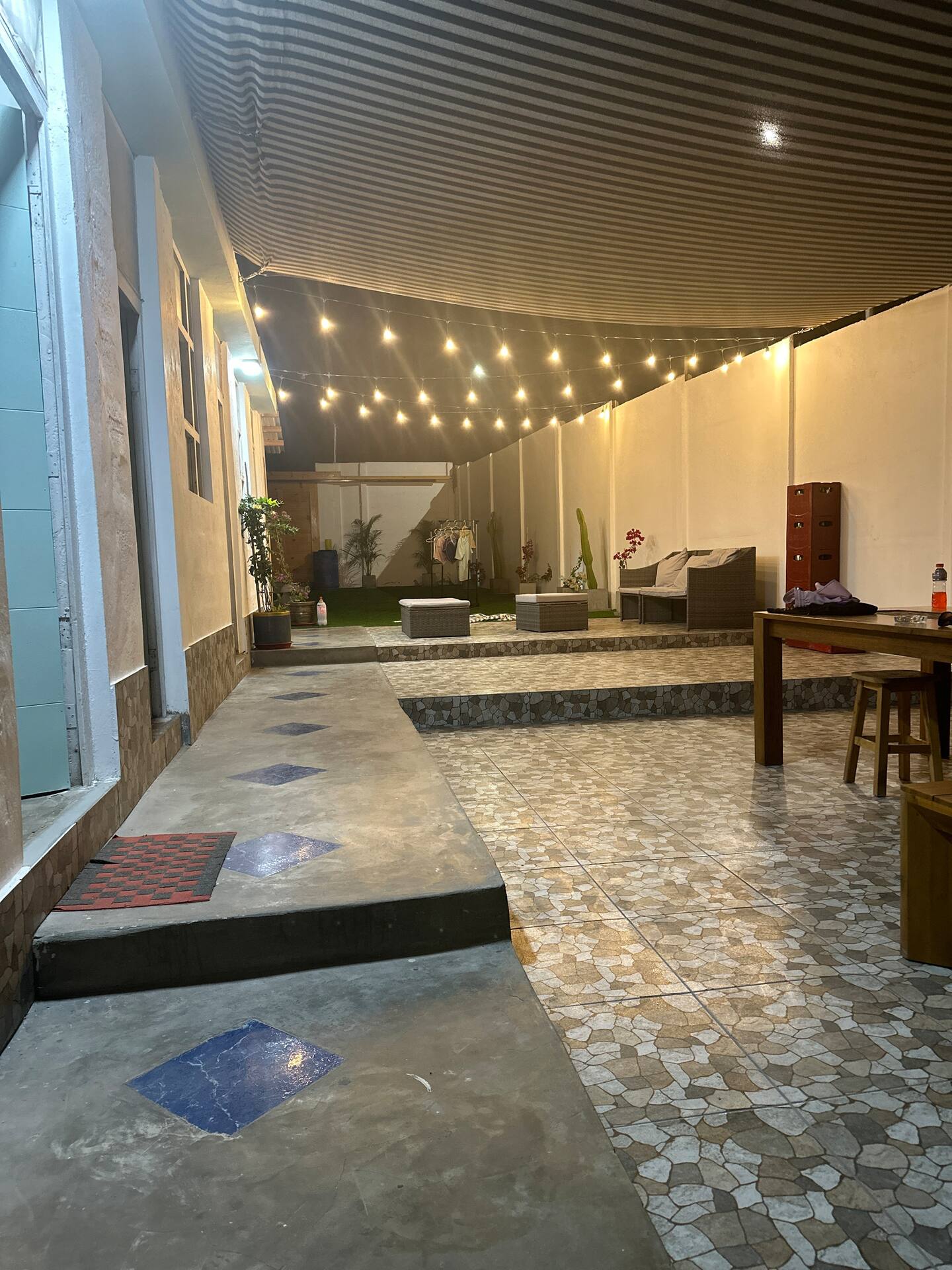 Terraza techada de noche con luces colgantes y sala exterior